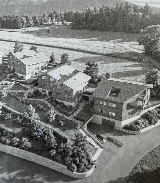 Aerial view of a residential complex with multiple houses, a garage, and landscaped gardens.