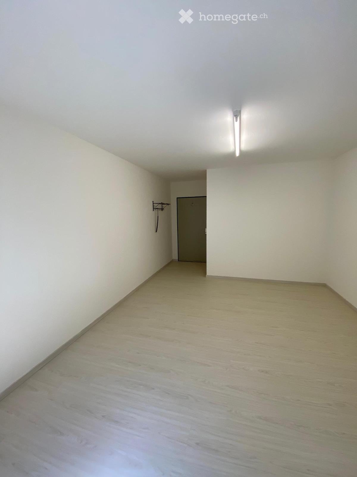 empty room, white walls, wooden floor, a door at the end