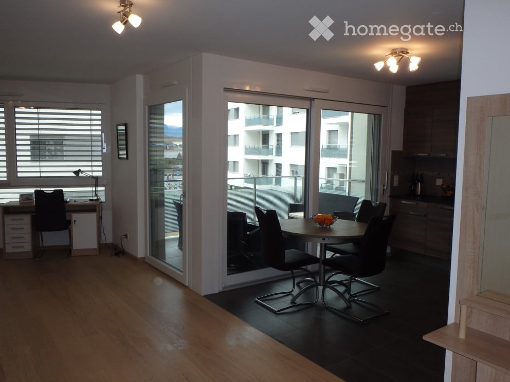 modern dining area with desk, glass wall to balcony, large windows, dining table, black chairs, black desk chair, lamps, kitchen, hardwood floors, black tile