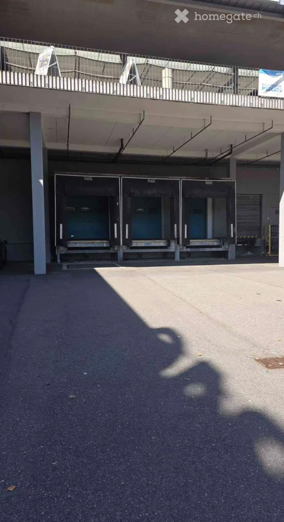 Multi-level parking structure with three garage doors and a metal railing on the upper level.