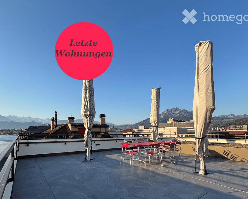 Roof terrace with outdoor furniture, umbrellas, and a scenic mountain view.