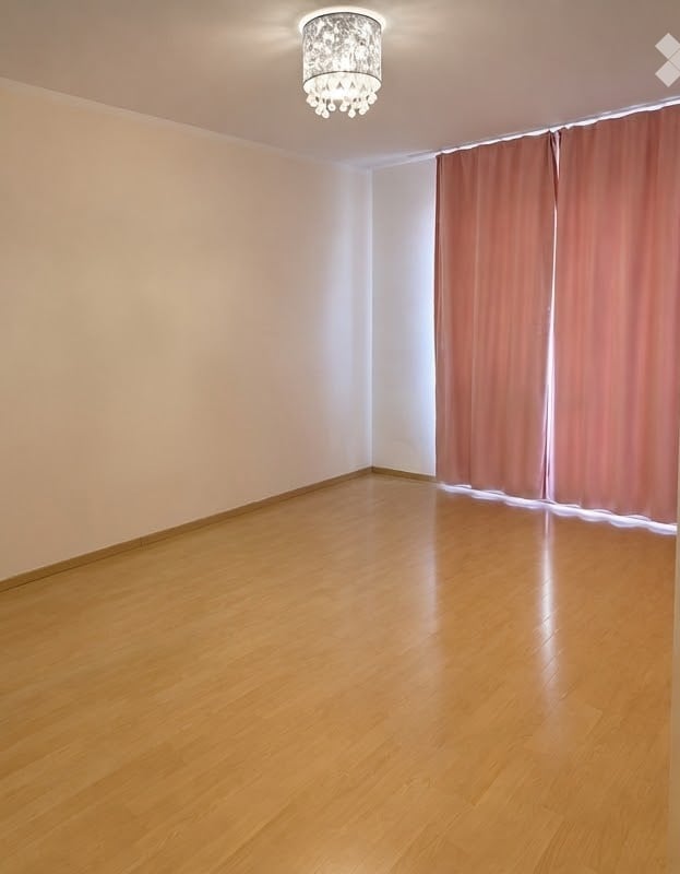 Empty room with wooden flooring, light-colored walls, and a decorative ceiling light fixture.