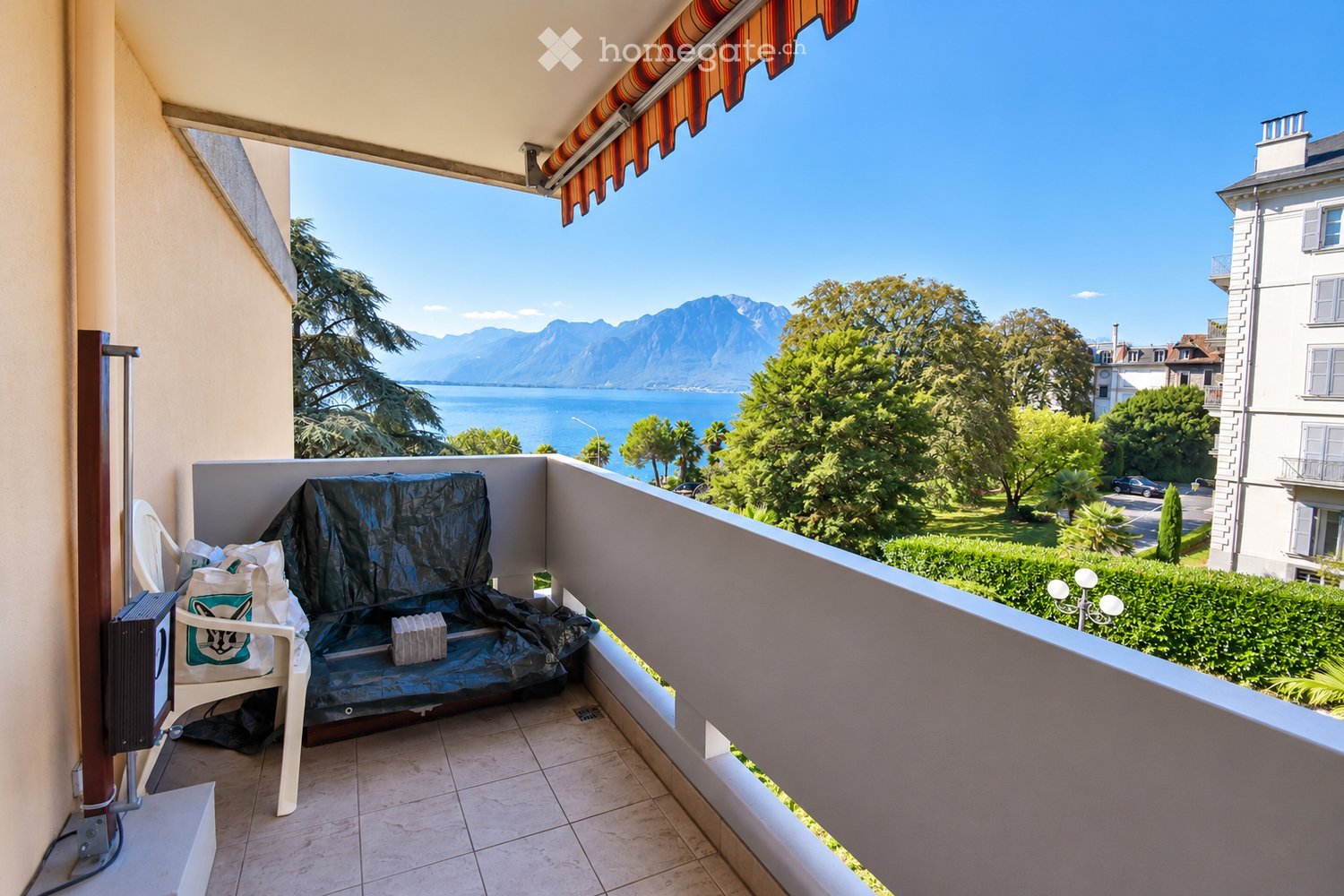 Balcony with tiled floor, covered seating area, and scenic mountain and lake view.