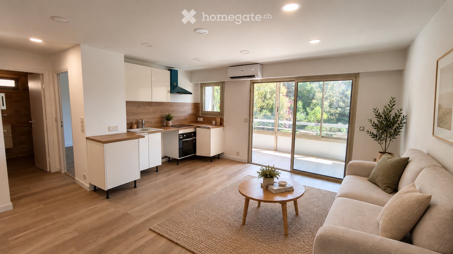 Modern living and kitchen area with light wood flooring, white cabinets, a sofa, coffee table, and a view through large windows.