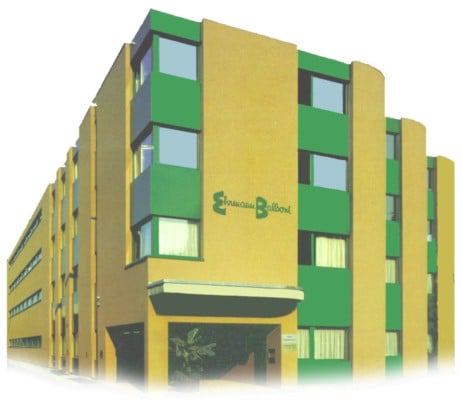 Modern multi-story building with yellow and green facade, large windows, and a sign reading "Sanjay Club Baldev".