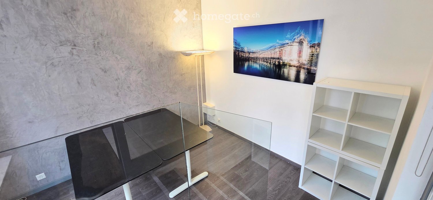 Modern room with a glass table, white shelving unit, floor lamp, and a large picture frame on the wall.