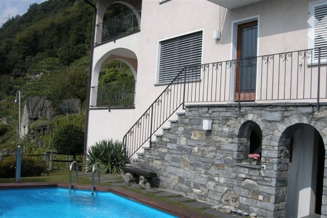 two-story house, stone wall, staircase with a handrail, balcony, swimming pool, mountain view