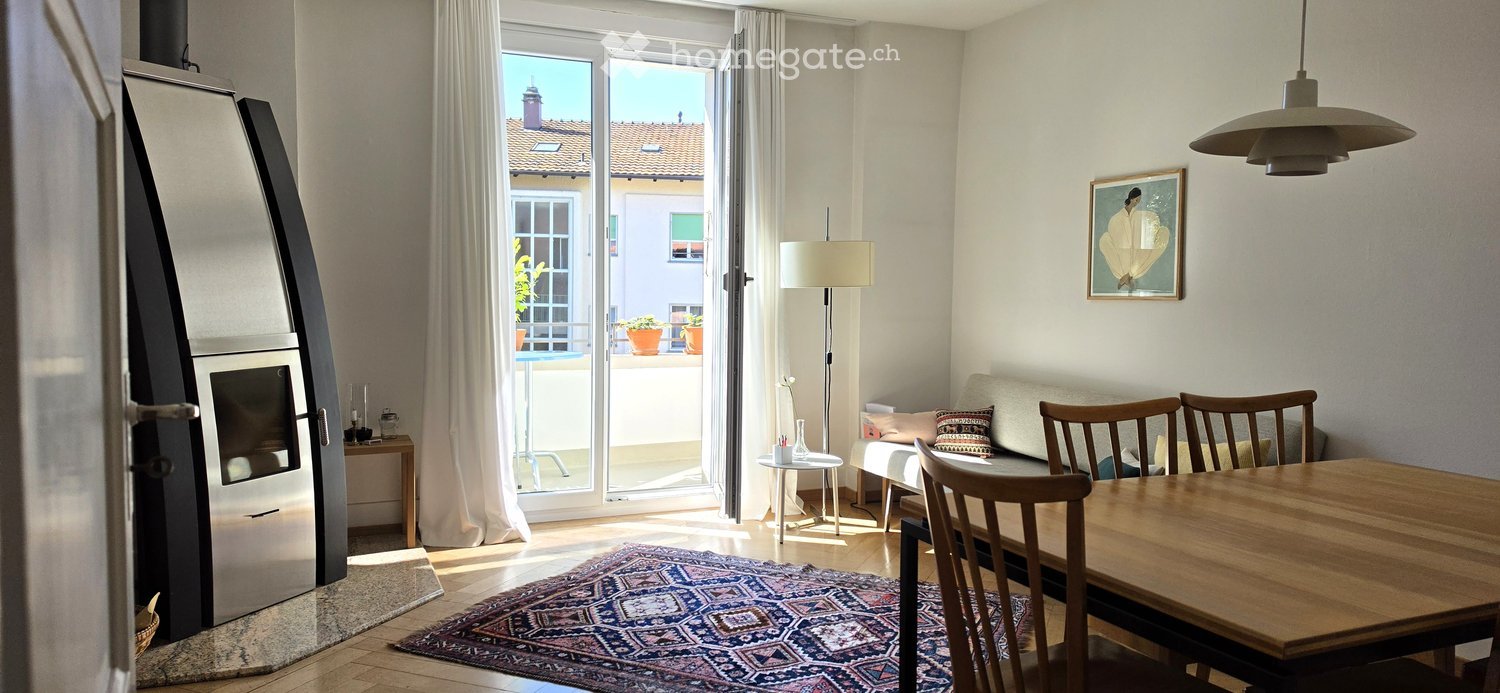 Bright living and dining area with a sofa, dining table, chairs, floor lamp, and a view to a balcony.