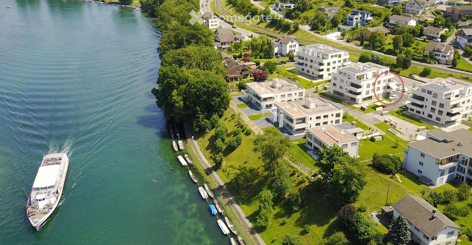 Aerial view of a lakeside residential area with multiple modern houses, a boat dock, and a boat on the water.