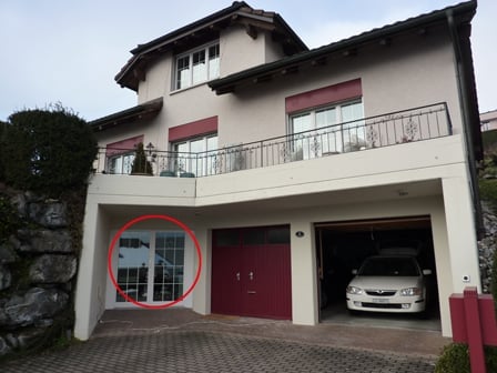 Two-story house with a garage, balcony, and a parked car in the driveway.