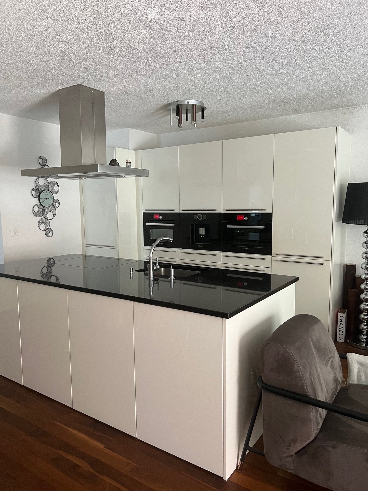 Modern kitchen with white cabinets, black countertop, stainless steel appliances, and a sleek design.