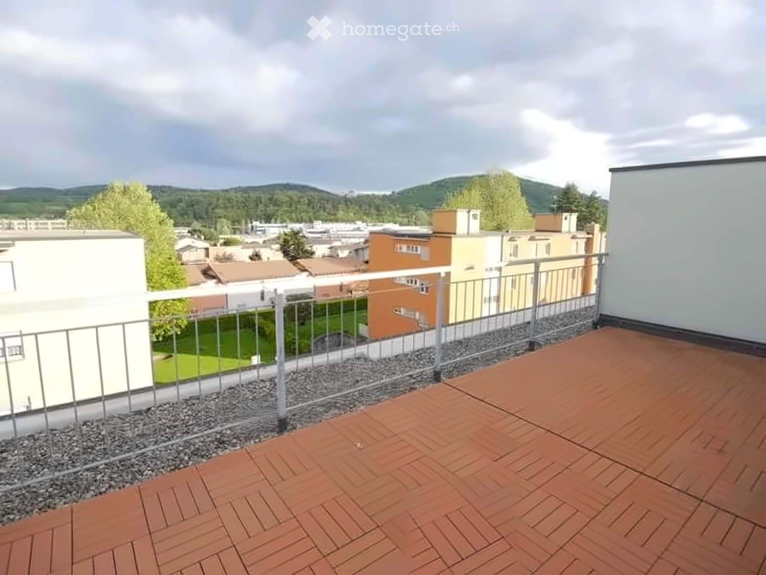 Terrace with wooden decking, metal railing, and a view of the town and surrounding hills.