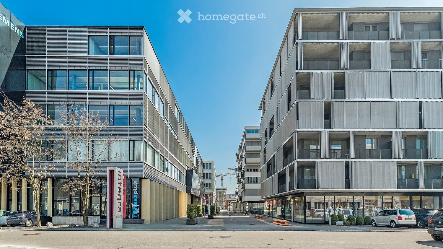 Modern multi-story building with large glass windows and balconies, featuring a contemporary design and urban setting.