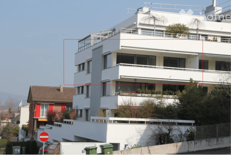 Modern multi-story apartment building with white facade, large windows, and balconies. The building features contemporary design with clean lines and a flat roof.