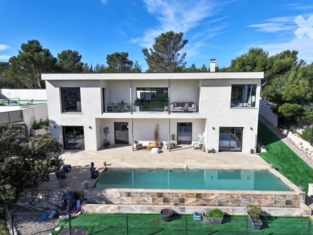 Modern two-story house with white exterior, large windows, and a swimming pool in the courtyard.