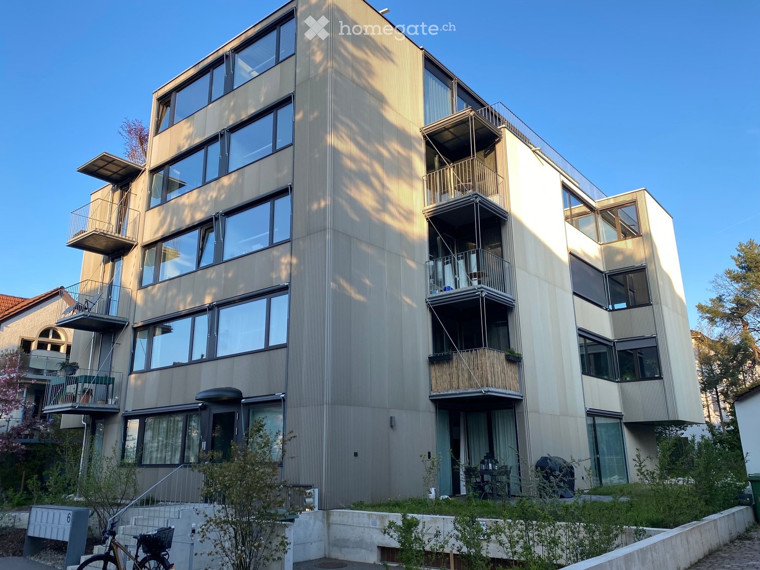 Modern multi-story residential building with large windows, balconies, and contemporary design.