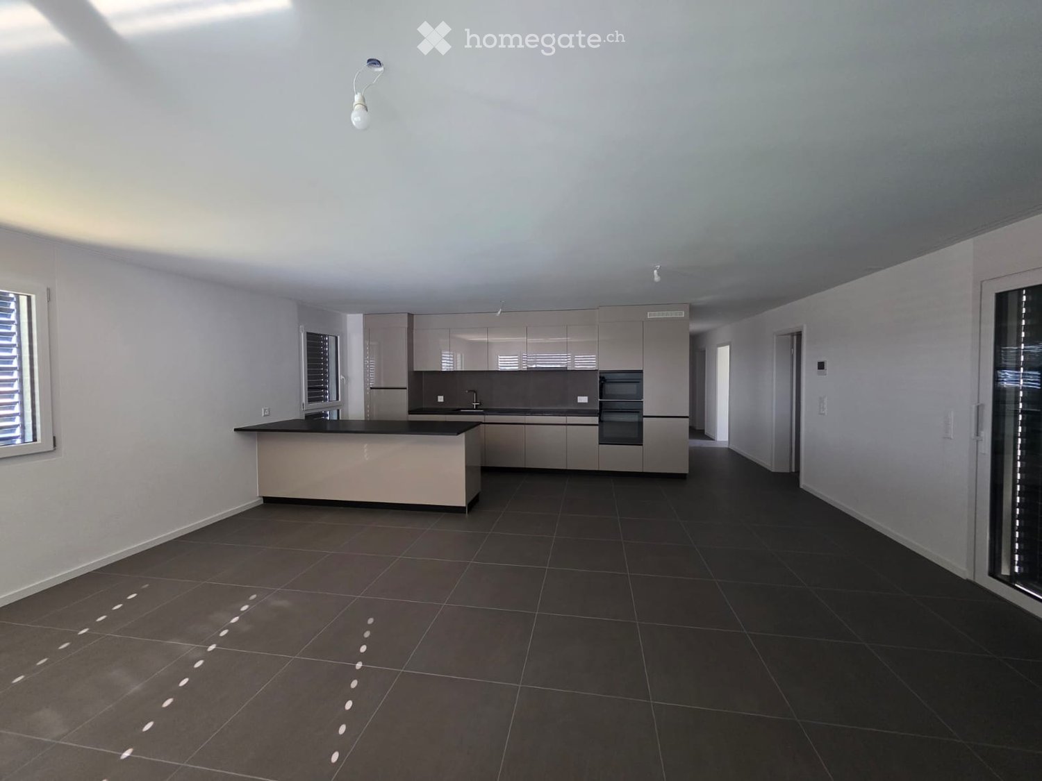 Modern kitchen with grey cabinetry, black tiled floor, and a central island.