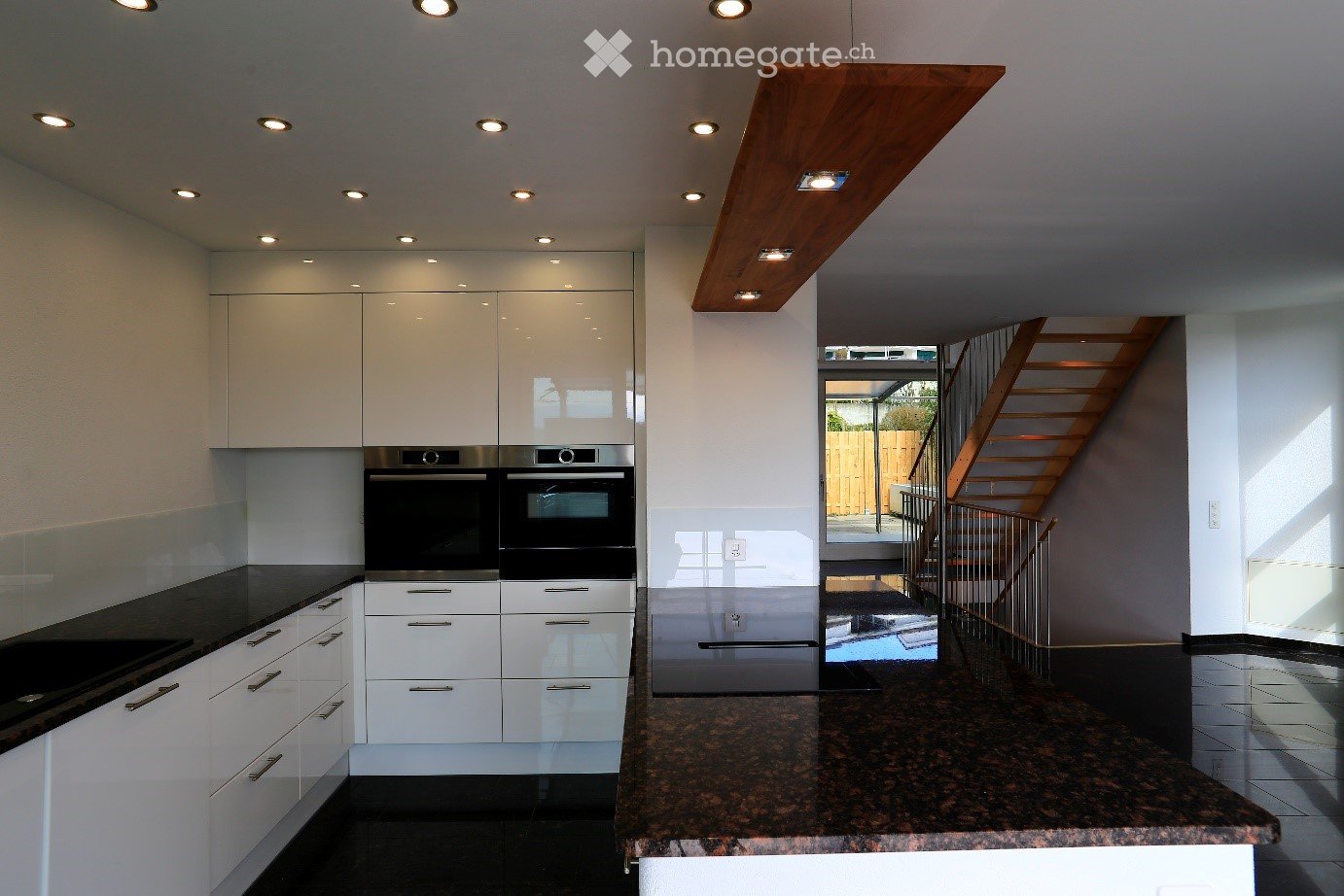 Modern kitchen with white cabinets, granite countertop, and built-in ovens.