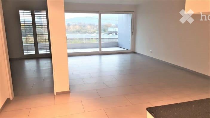 Empty room with large sliding glass doors leading to a balcony, tiled floor, and neutral-colored walls.