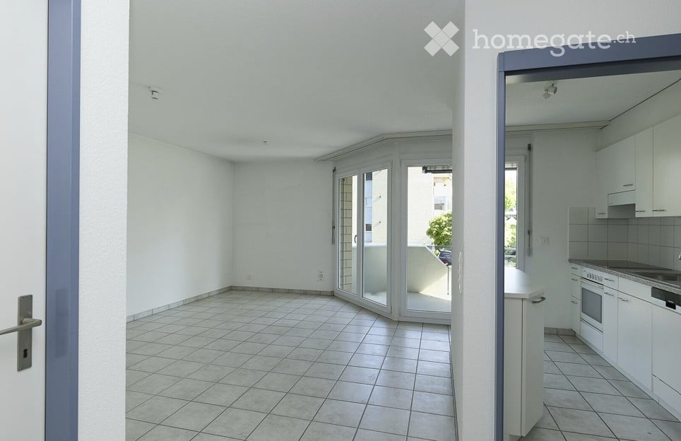 Empty room with tiled floor, white walls, and sliding glass doors leading to a balcony.