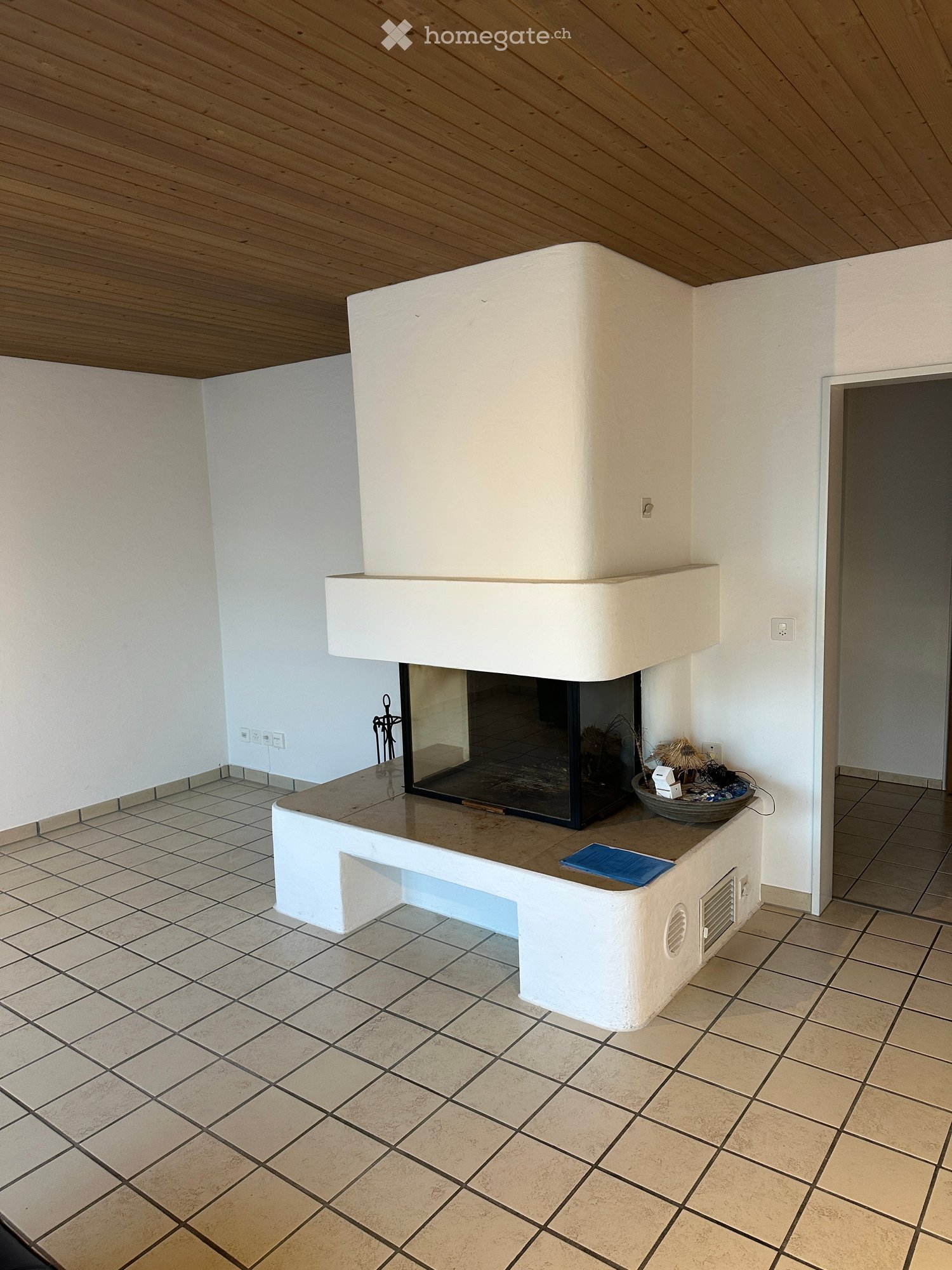 Modern fireplace with white surround, tiled floor, and decorative items on mantel.
