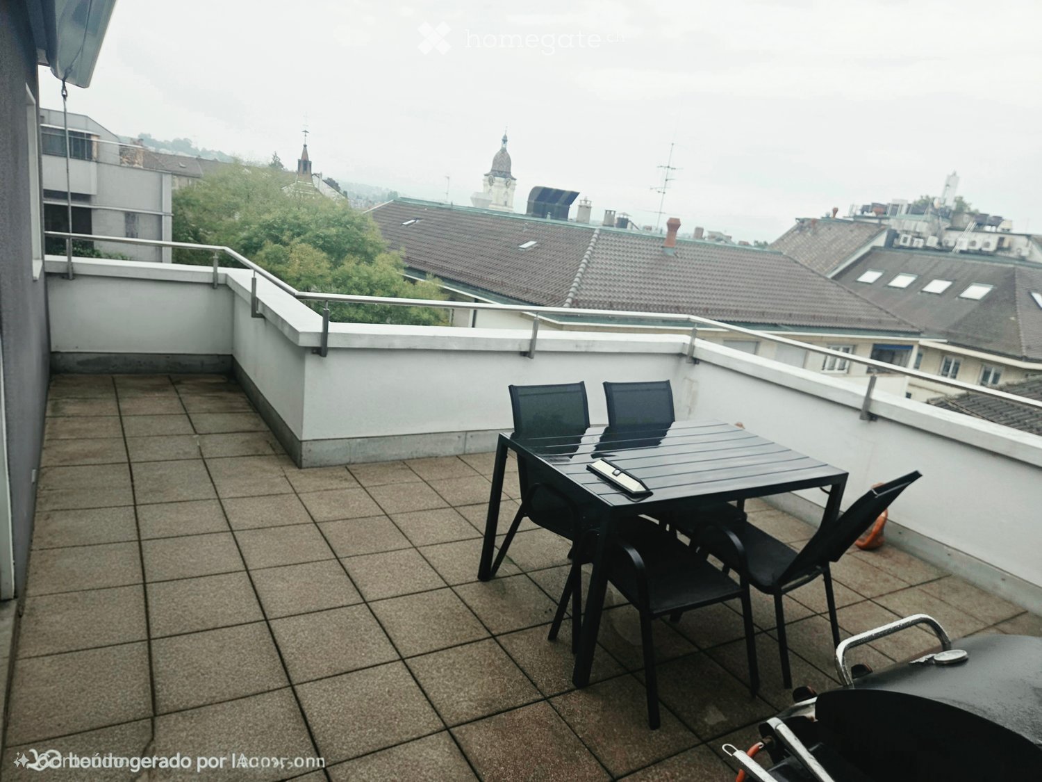 Balcony with tiled floor, metal railing, and a small table with chairs.