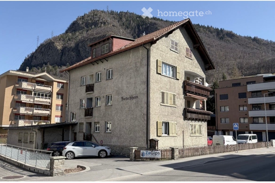 Multi-story residential building with a textured facade, multiple windows, balconies, and a name sign reading "Bieschborn".