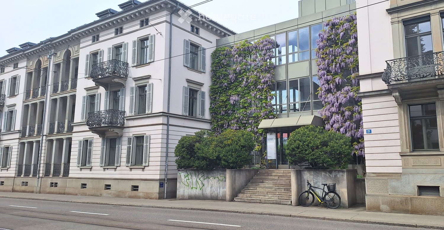 Multi-story residential building with classical architecture, large windows, balconies, and climbing wisteria vines.