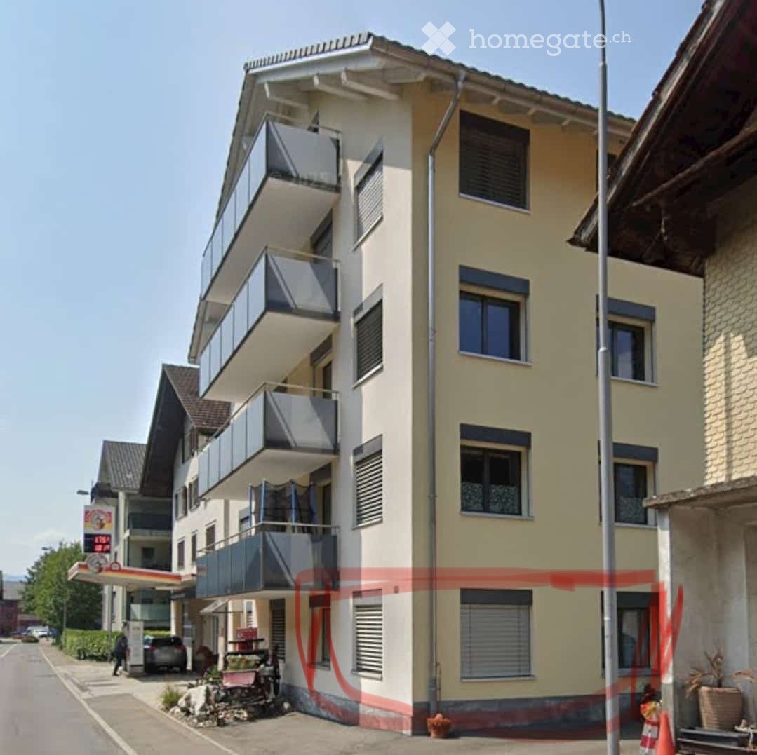 Modern multi-story building with balconies, light yellow facade, and multiple windows.