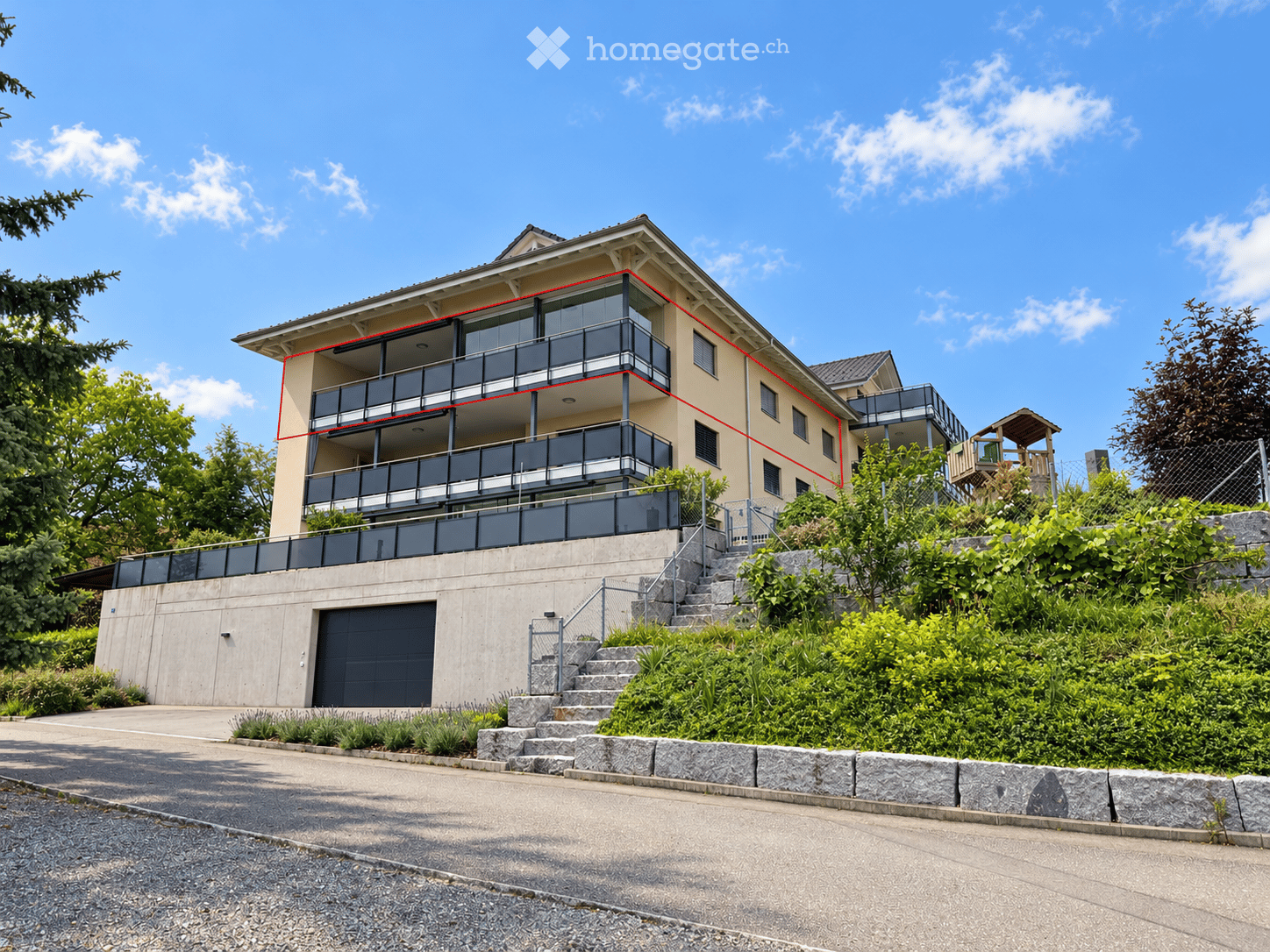 Two-story house with balconies, garage, and landscaped garden area.