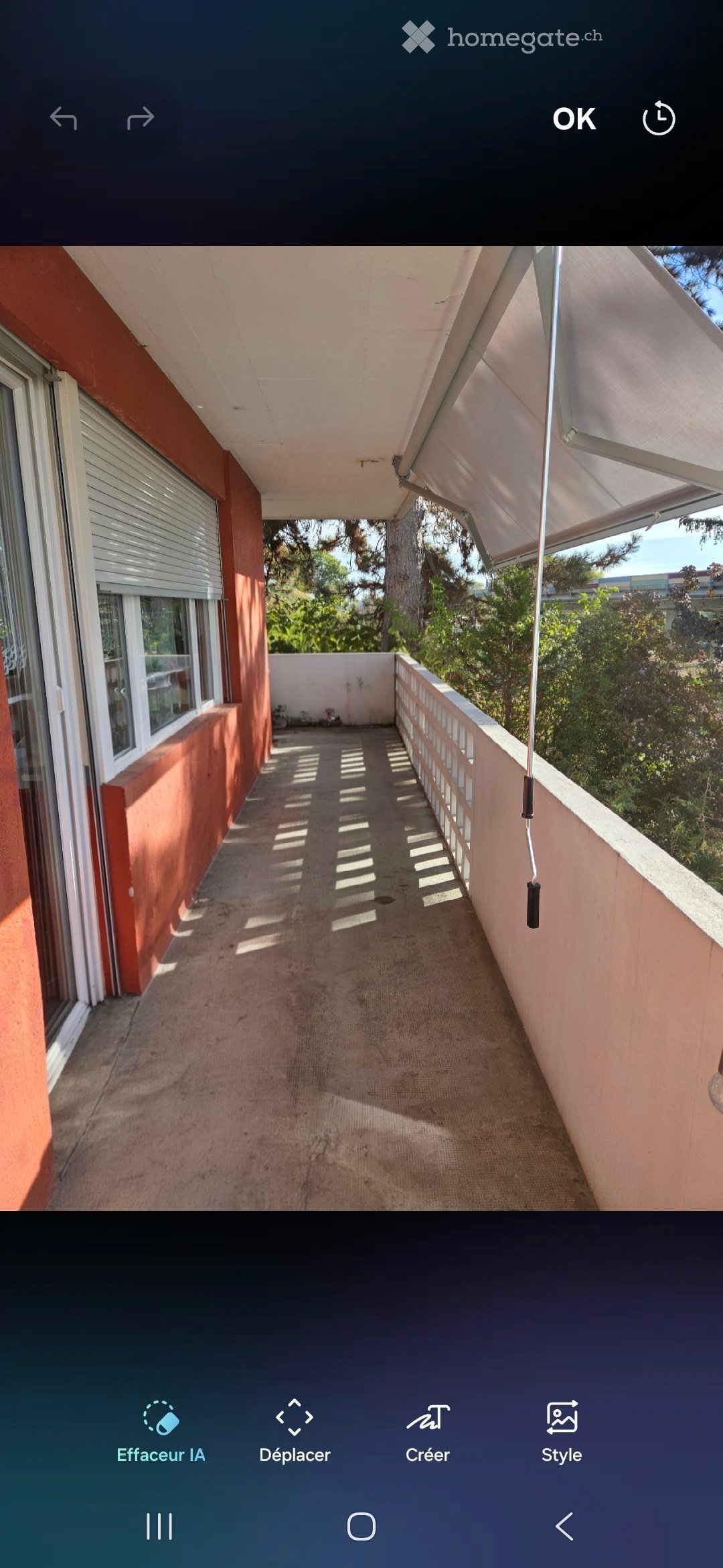 Balcony with beige carpet, white railing, and retractable awning, overlooking greenery.