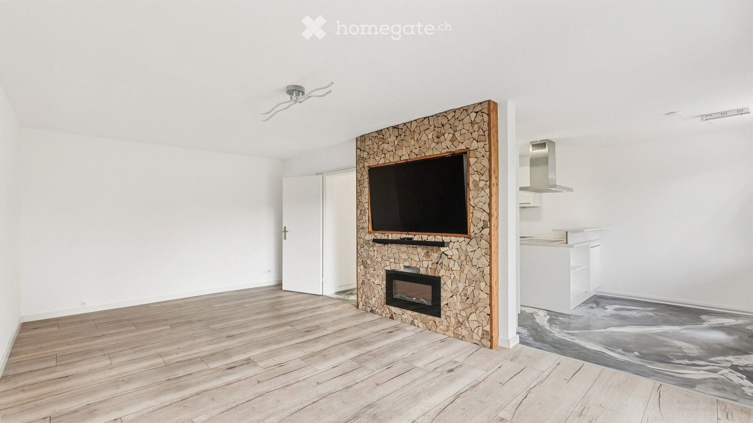 Open-plan living and dining area with a fireplace, television, and modern kitchen area.