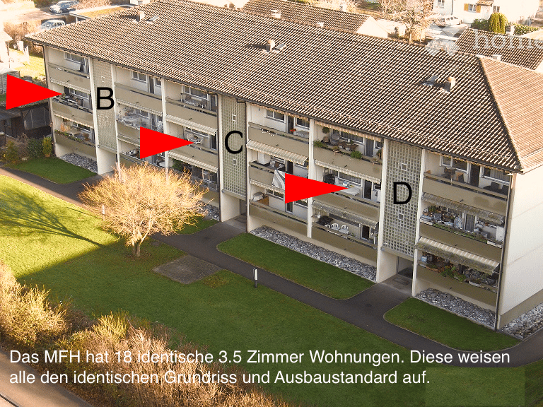 A multi-story apartment building with multiple balconies and a well-maintained lawn in front.