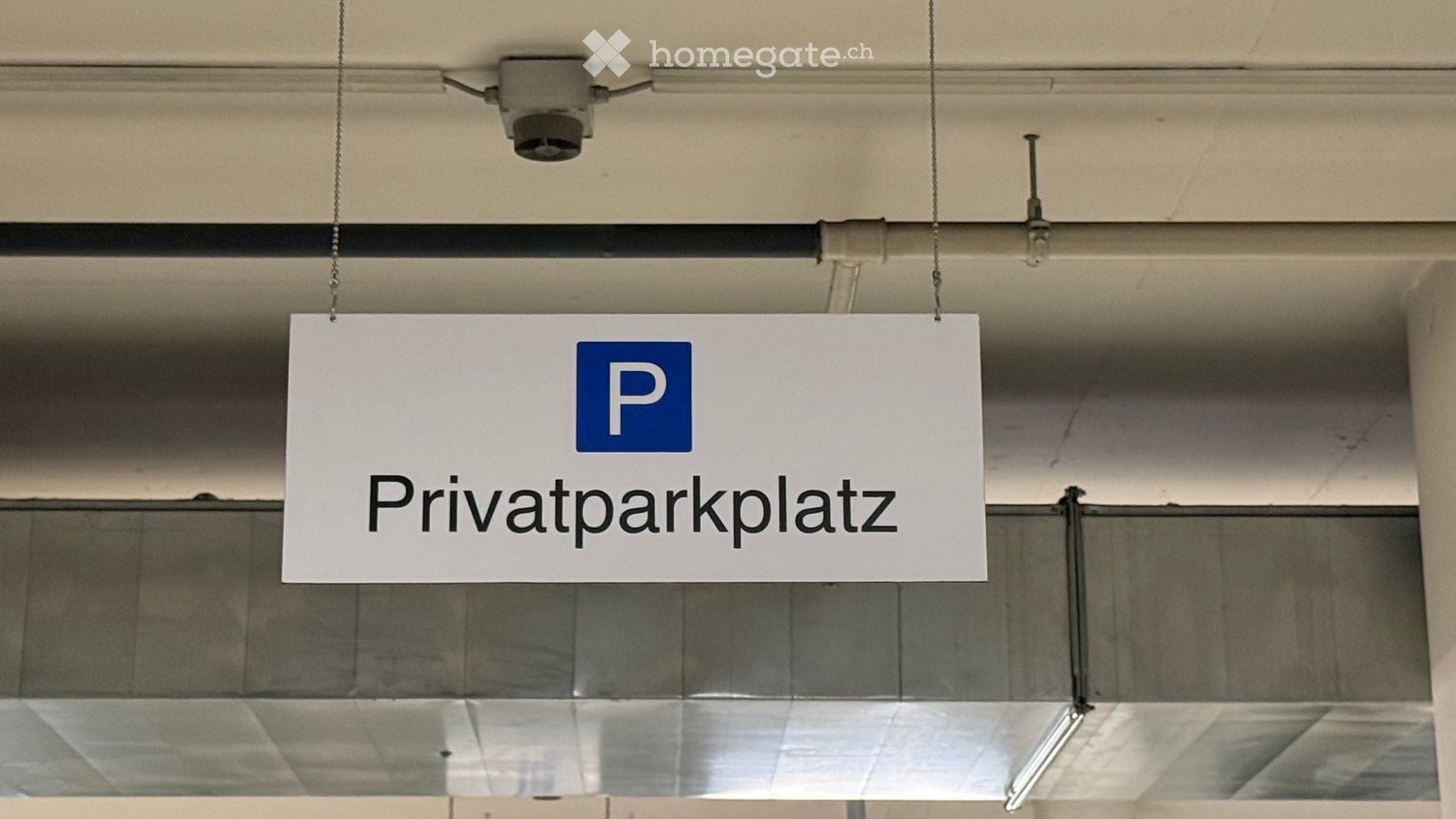 A sign reading "Privatparkplatz" (private parking space) is suspended from the ceiling in a building corridor.