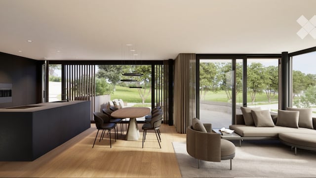Open-plan living and dining area with large windows offering a view of the outdoors, featuring a modern sofa, ottoman, coffee table, dining table, and chairs.