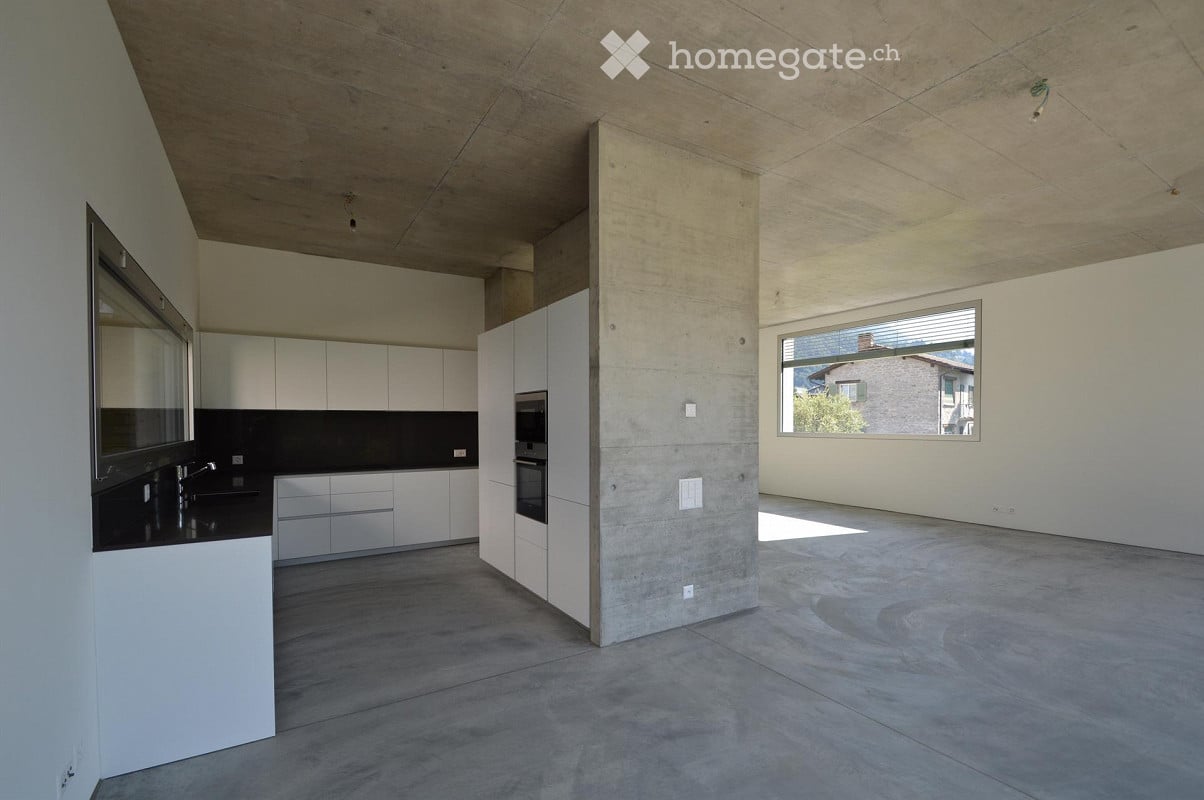Modern kitchen with white cabinets, stainless steel oven, and a large window overlooking a view.