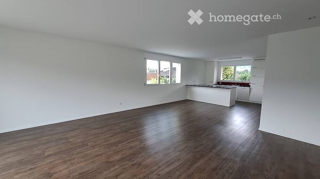 Empty room with wooden flooring, white walls, and large windows. No furniture or equipment present.