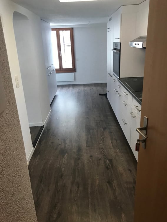 Empty room with wooden flooring, white walls, and a window with wooden frame. No furniture or equipment present.