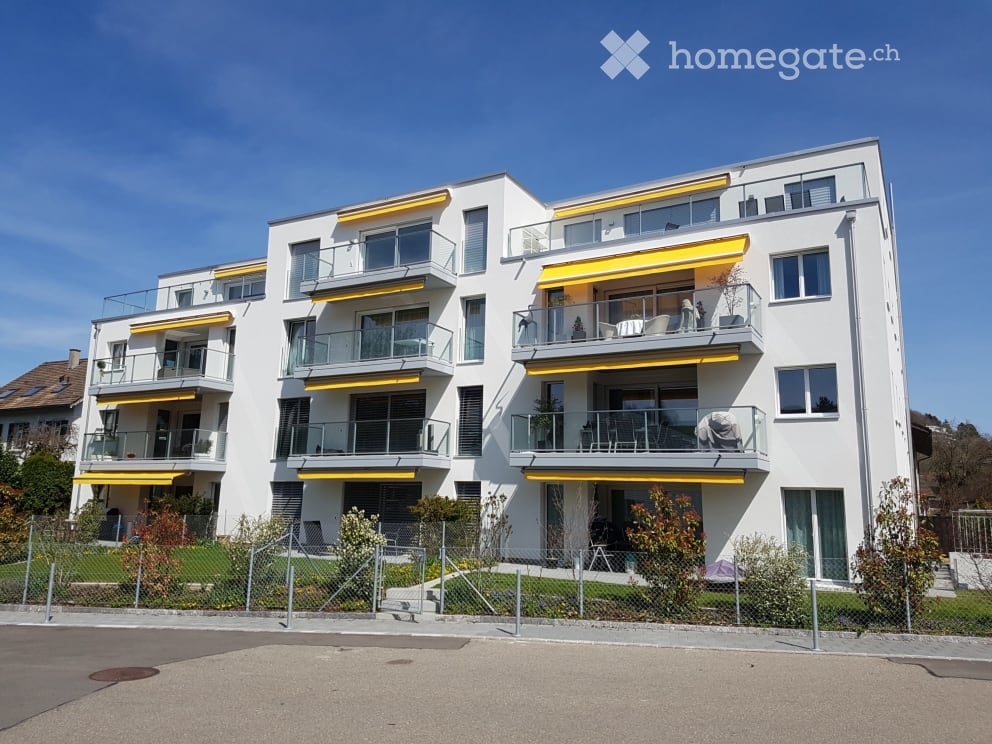 Modern multi-story apartment building with white facade, yellow accents, and multiple balconies.