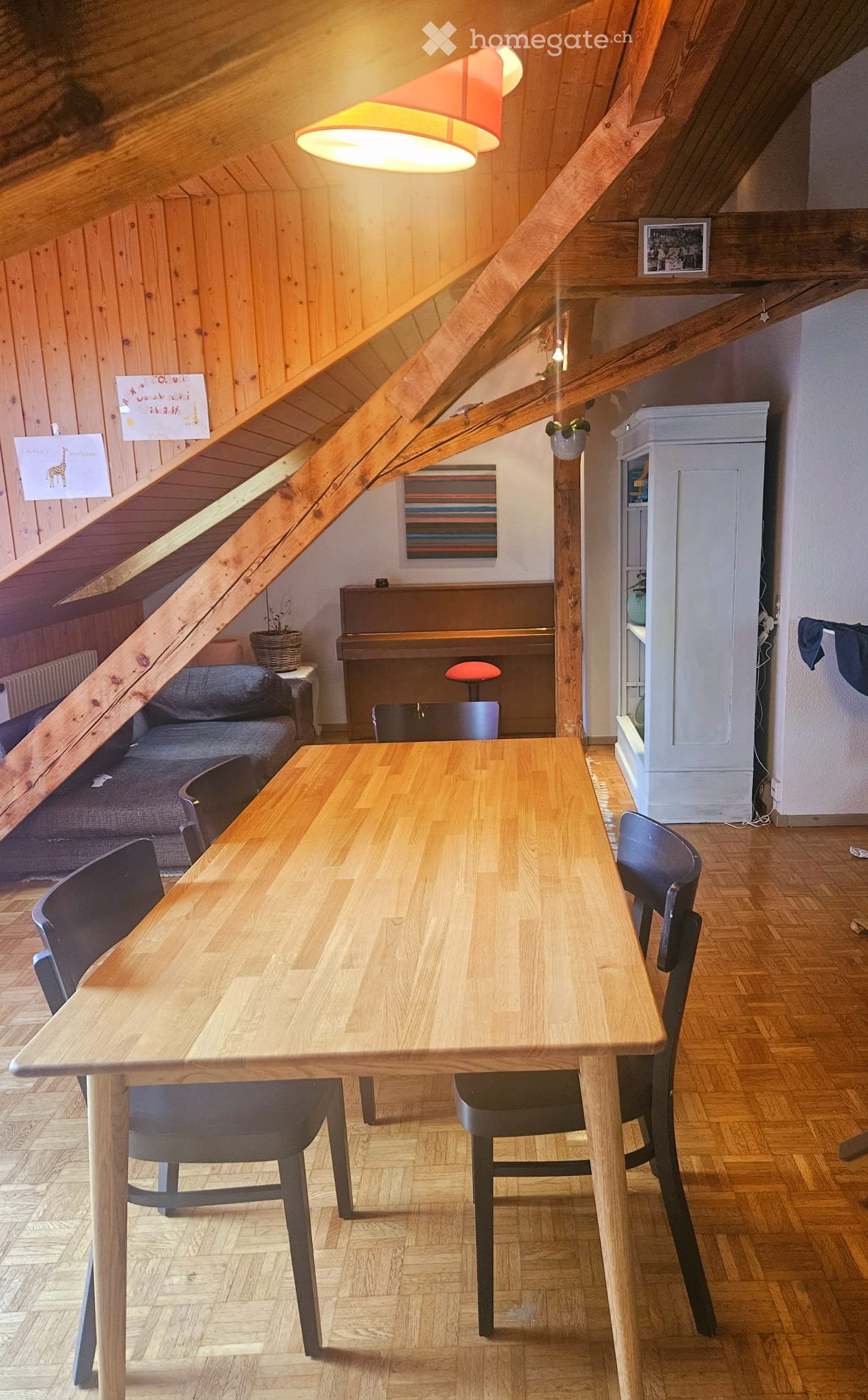 Dining area with wooden table and chairs, piano, cabinet, couch, and various decorative items.