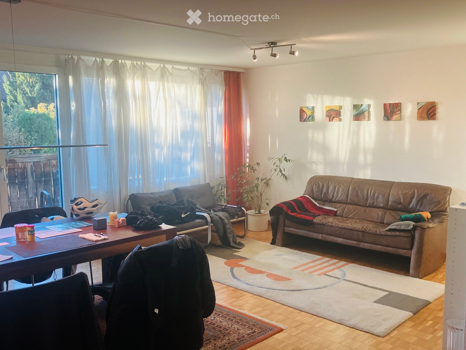 Living room with a large window, two sofas, a coffee table, a plant, and artwork on the wall.