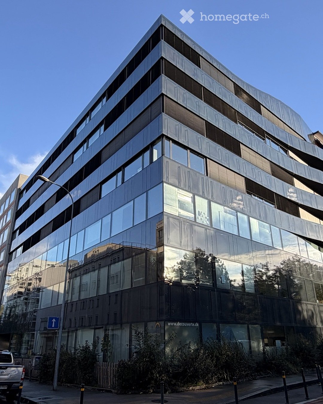 Modern multi-story building with reflective glass windows and sleek metallic accents, featuring a contemporary architectural design.