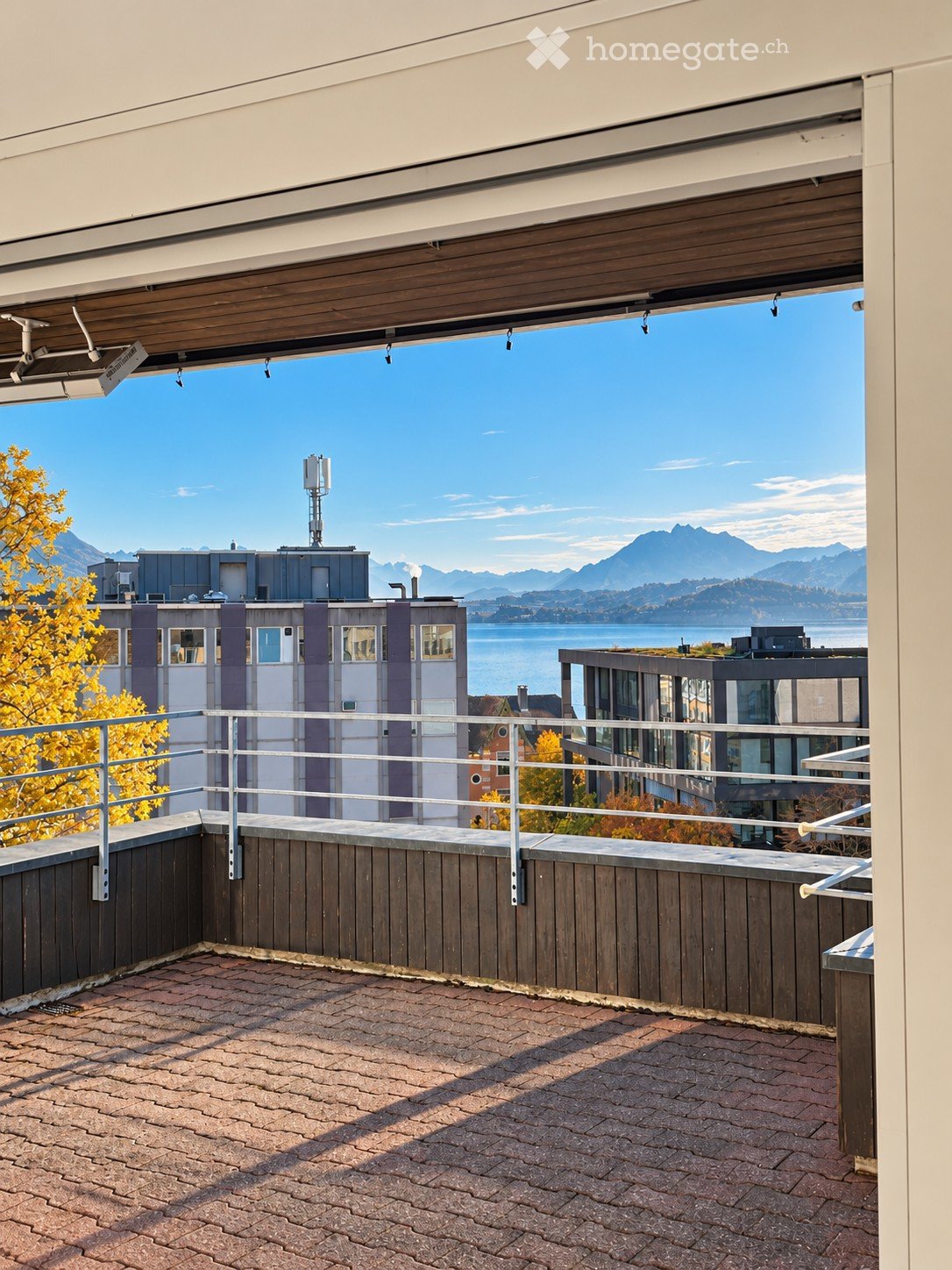 Balcony with wooden decking, metal railing, and scenic view of mountains and lake.