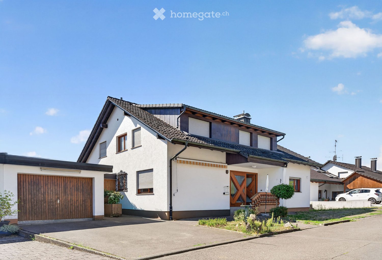 Two-story house with white exterior, dark roof, garage, and small garden area.