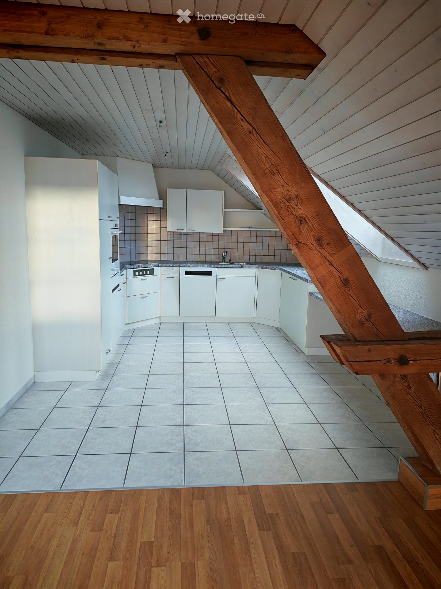 Modern kitchen with white cabinets, a sink, and a dishwasher, featuring a wooden staircase leading to an upper level.