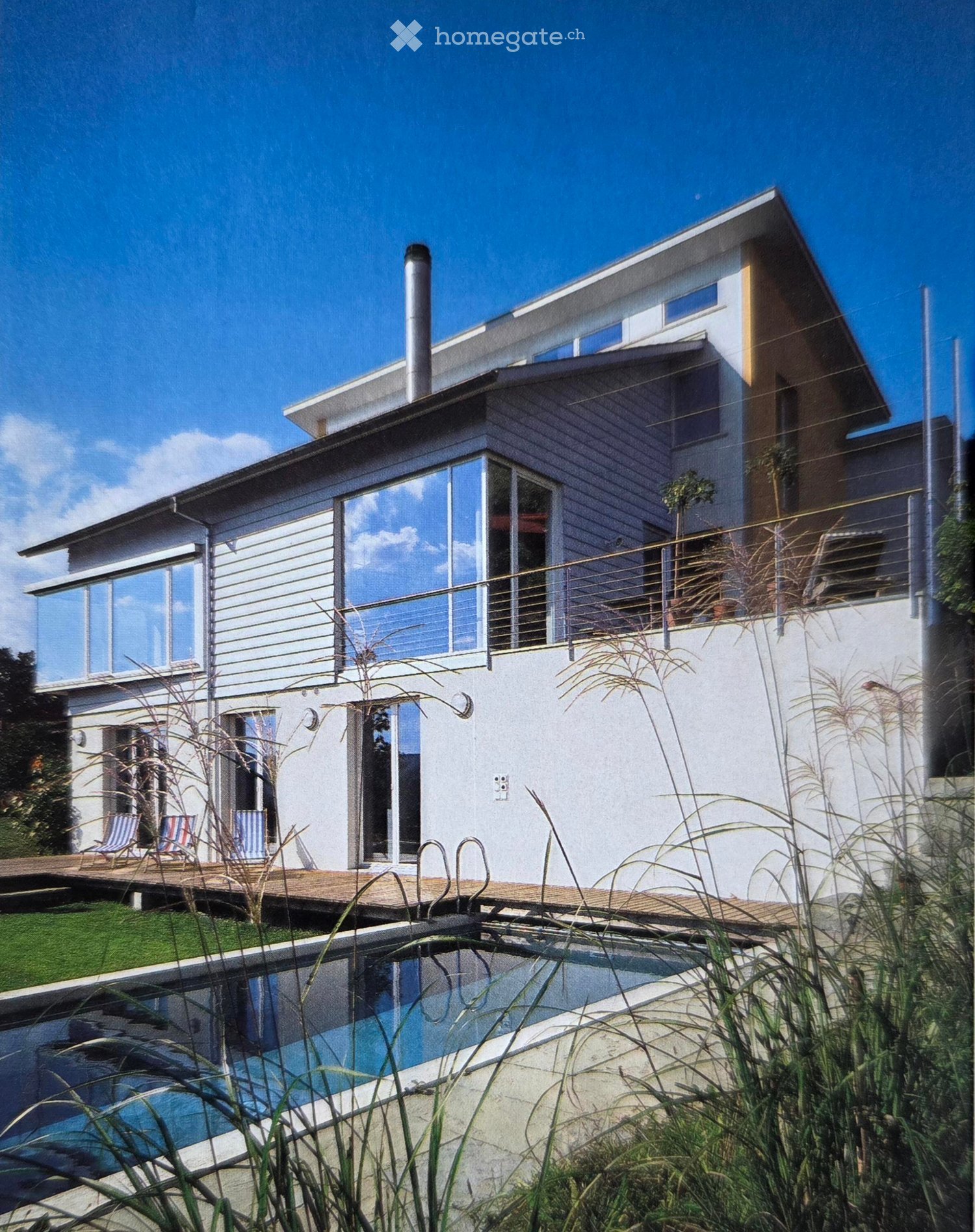 Modern house with a pool, balcony, large windows, wooden fence