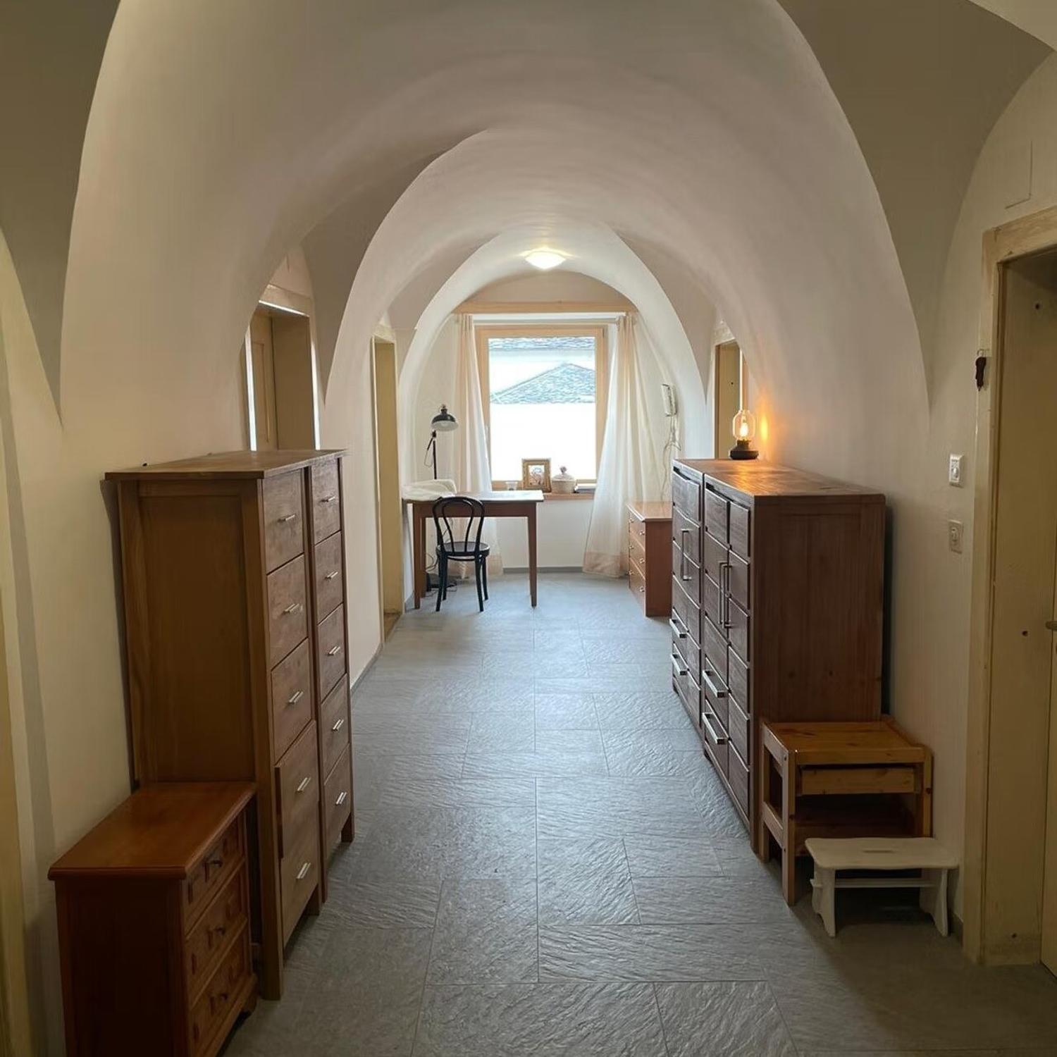 long hallway, vaulted ceiling, desk, wooden cabinet, small stool