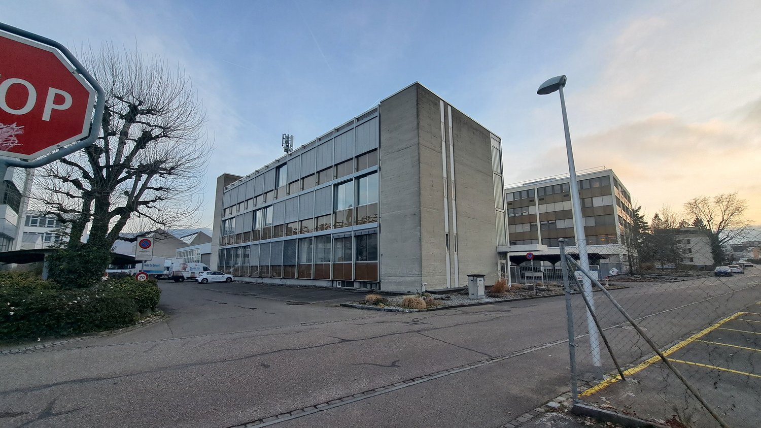 4 story office building, grey color, glass windows, parking lot, trees, street light