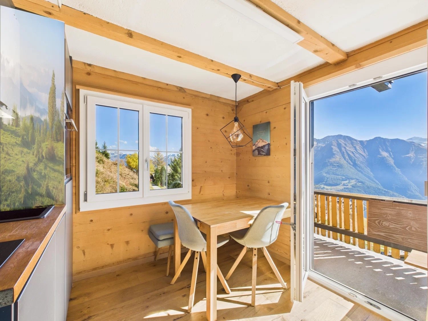 Wooden table, 2 chairs, windows, balcony, wooden floor, open door, lamp