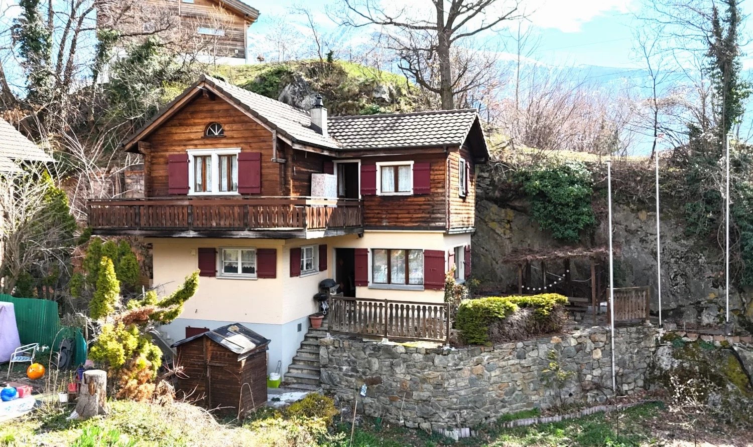 2 story wooden house, red shutters, balcony, stone wall, stairs, chimney